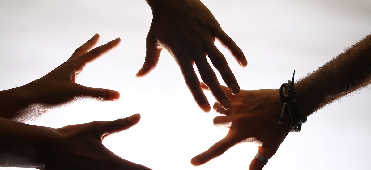 Five extended hands shown against the light.